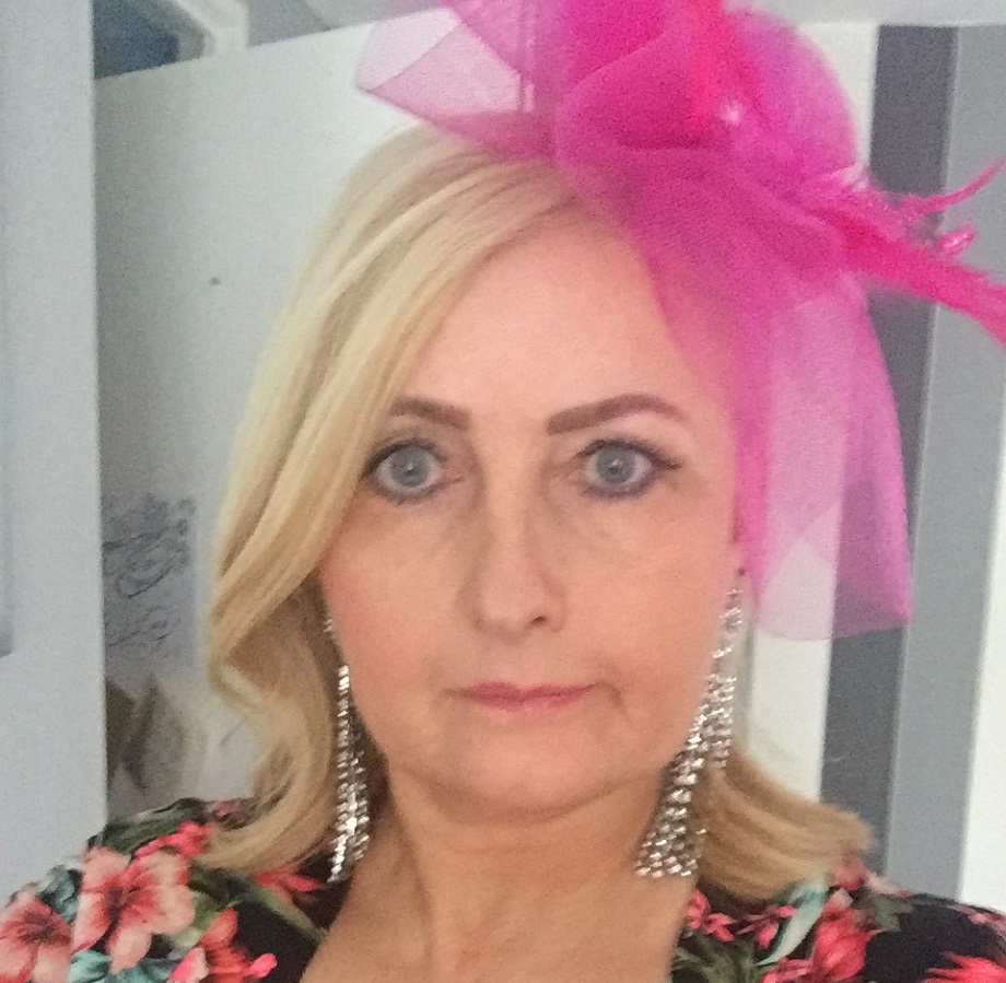 A woman wears a pink fascinator.