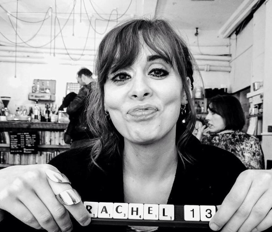 A woman holds up Scrabble tiles reading "Rachel".