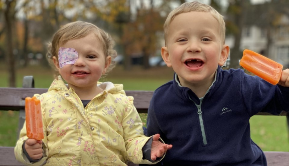 Two toddlers on a bench eating lollies