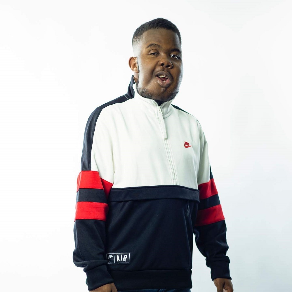 Olu who has cystic hygroma wears a red, white and blue sports jacket and stands against a white background