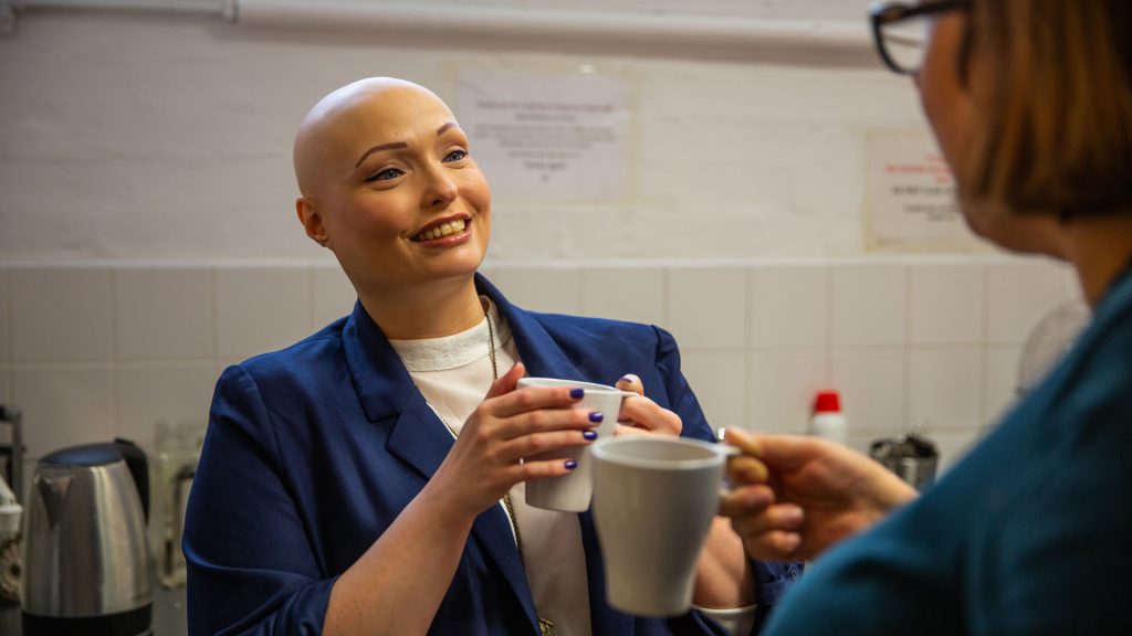 A woman smiles as she speaks with a colleague on their tea break