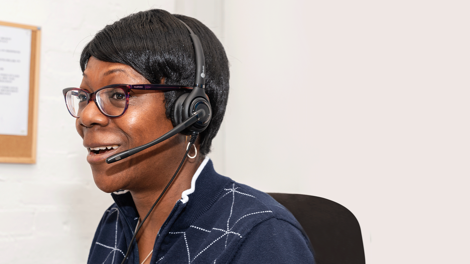 Dola sitting in an office, wearing a headset and smiling