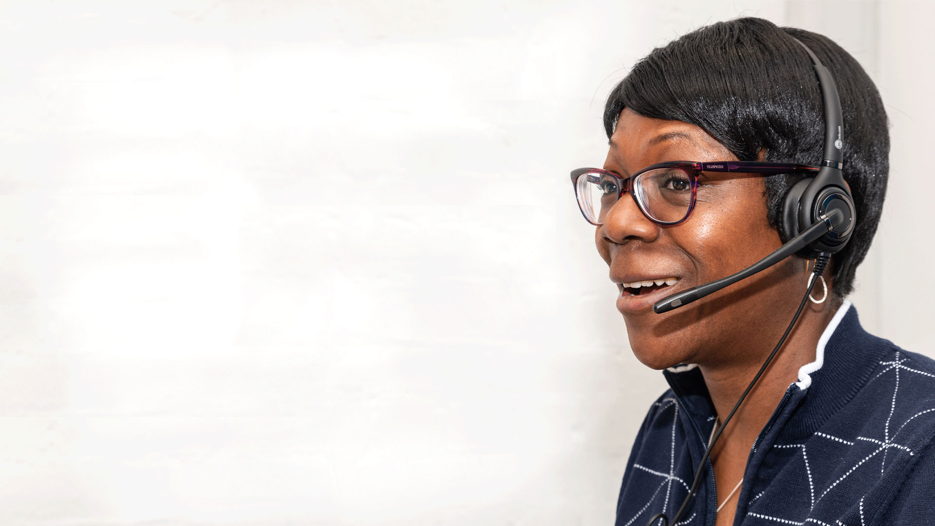 Helpline operative in profile, wearing headset and smiling