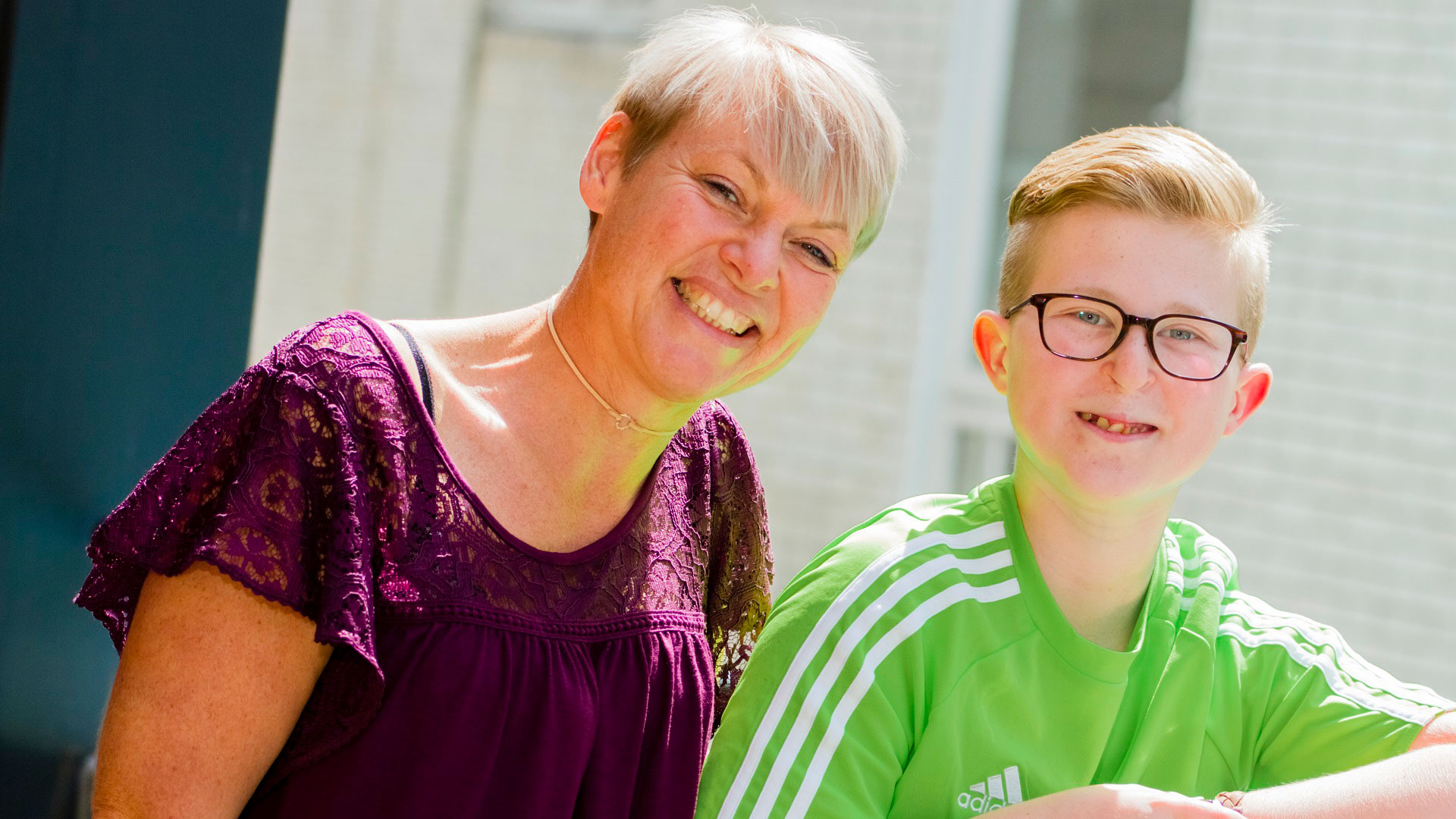 A woman and a boy smiling, both looking to camera