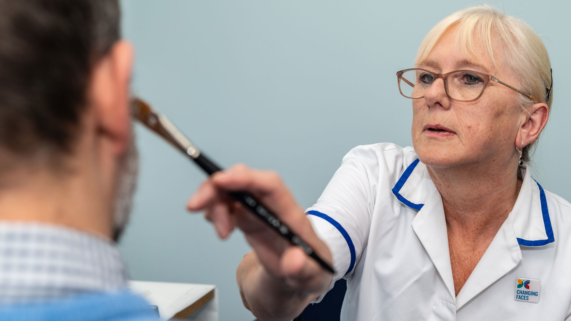 A skin camouflage practitioner applying skin camouflage to a service-user