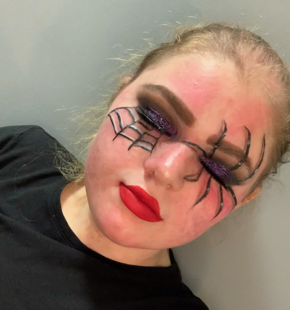 Campaigner Emma who has long blonde hair and a visible difference, wearing spider and web make up around her eyes