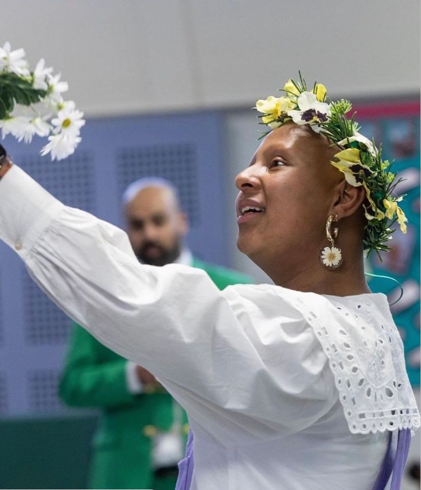 Jess acting in Hamlet - wearing a flower crown and gazing at a bouquet which she holds in the air. She is wearing all white.