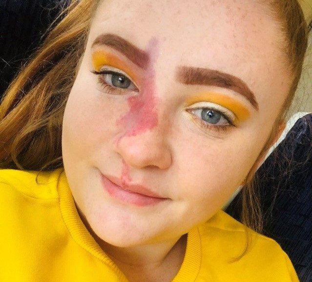Close up selfie of Caitlin, who wears a yellow jumper and has matching yellow eye shadow on.