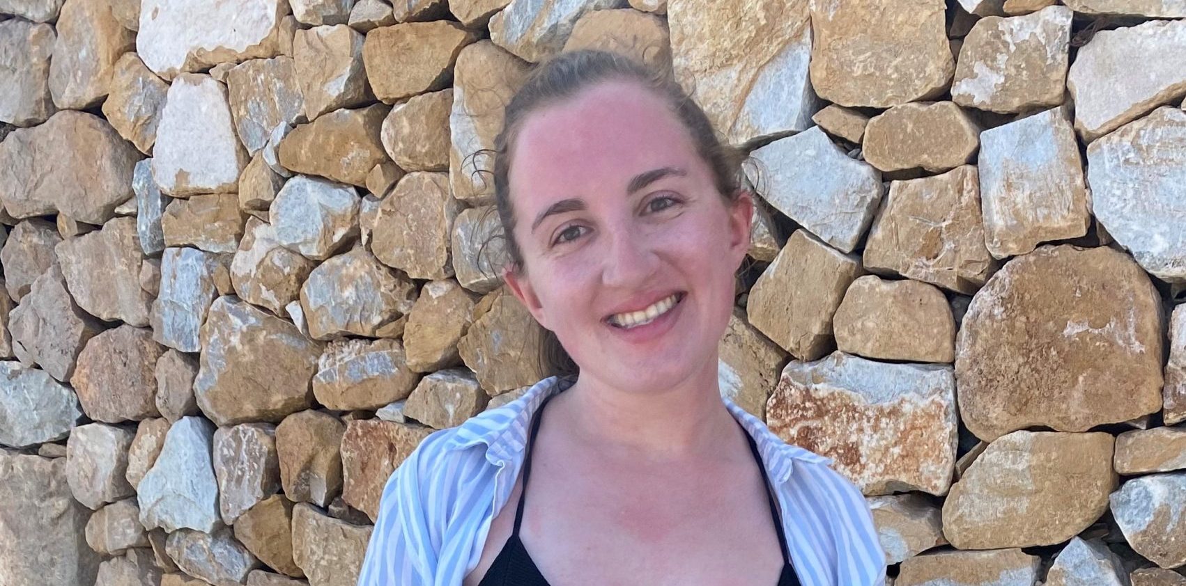 A young white woman with brown hair smiles at the camera.