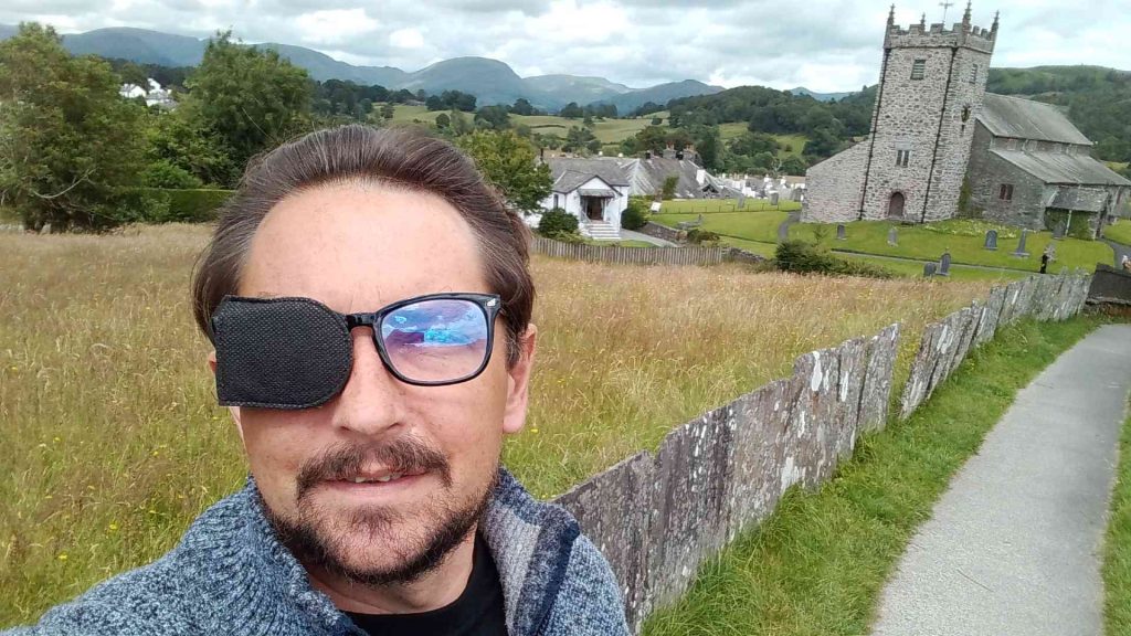 A man with an eye patch in the countryside near a church