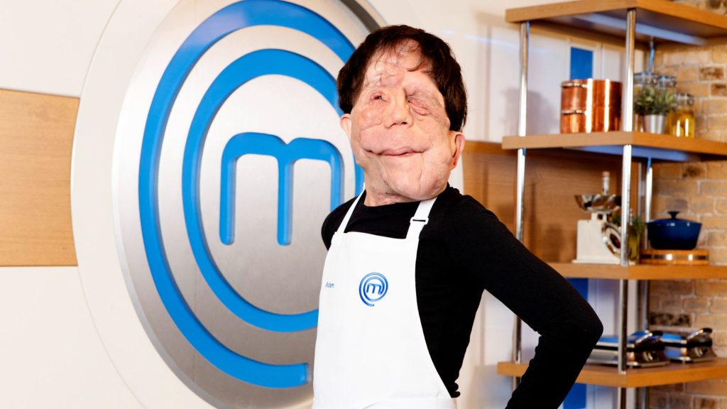 Ambassador Adam stands in front of the MasterChef logo in an apron
