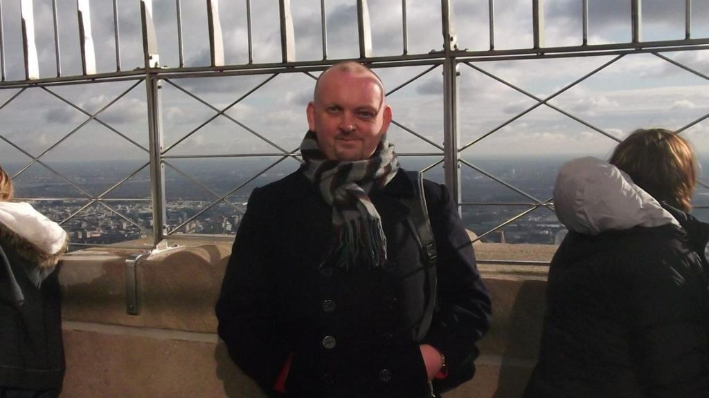 A man with a visible difference standing at the top of the Empire State Building