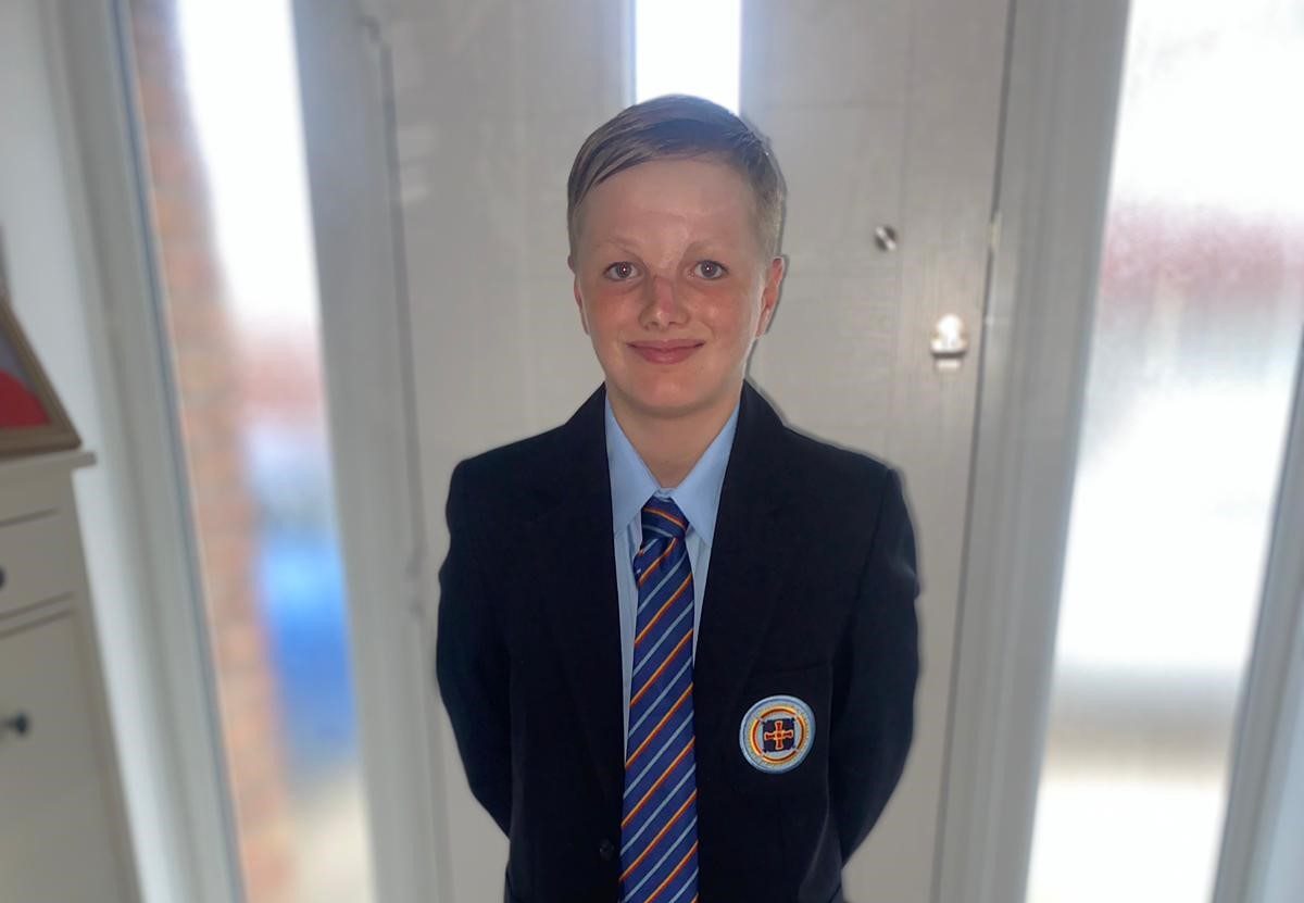 Charlie in his new school uniform. He is blonde and has scarring on his nose and forehead.