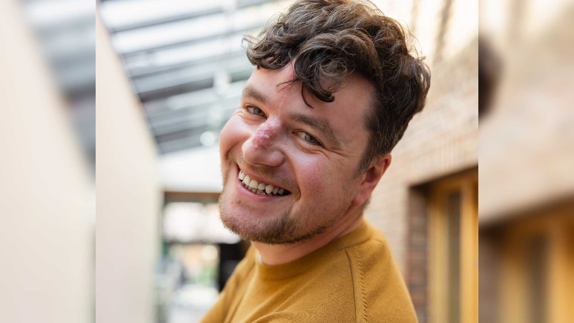 Building confidence after acquiring a scar hero image. A head and shoulder photo of David. He smiles at the camera. David has scarring on his nose and forehead, and is wearing a yellow jumper.