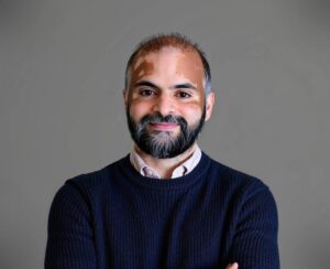 Amit smiling at the camera. He has vitiligo on his face.