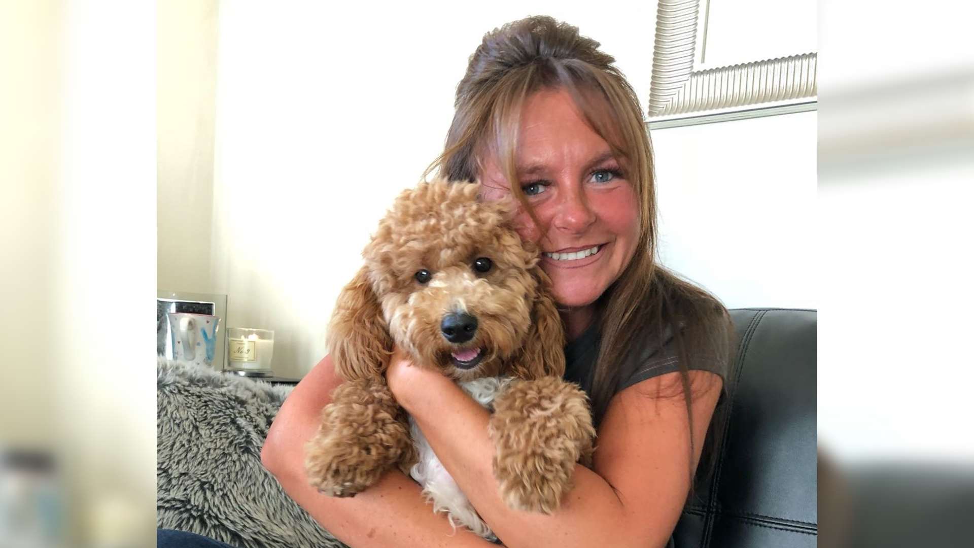 Charlotte sits hugging her dog smiling at the camera.
