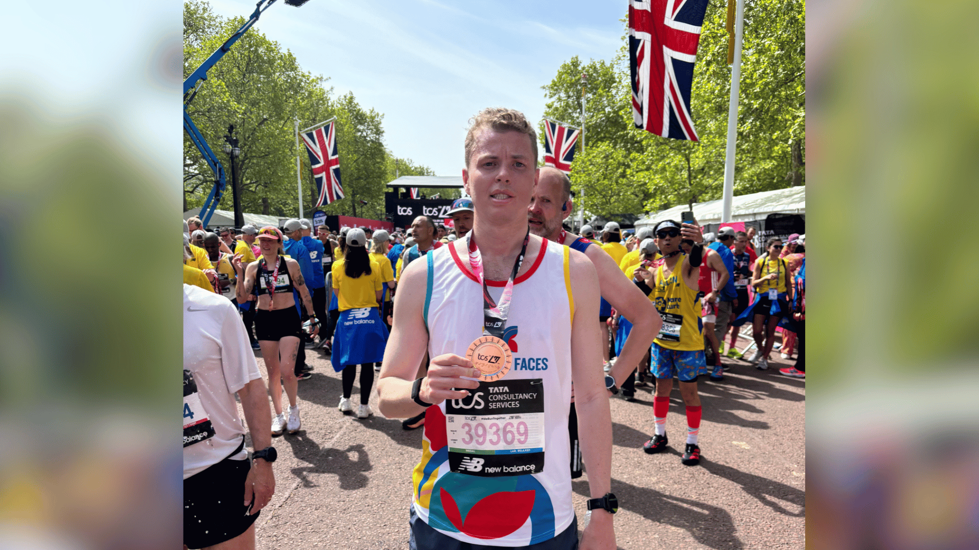 Jack holding his medal after finishing the London Marathon. He's wearing a Changing Faces running vest. Jack was born with facial palsy which he's had throughout his life.