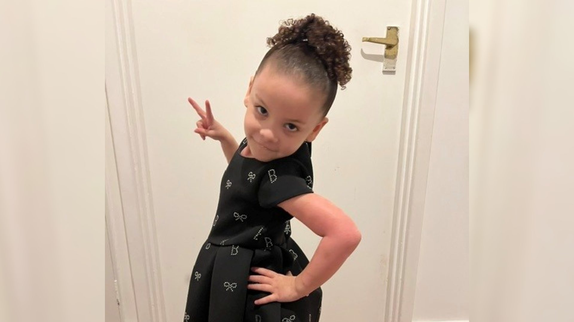 A photo of Nyah posing with a hand on her hip and a peace sign. Nyah is a little girl who has eczema.