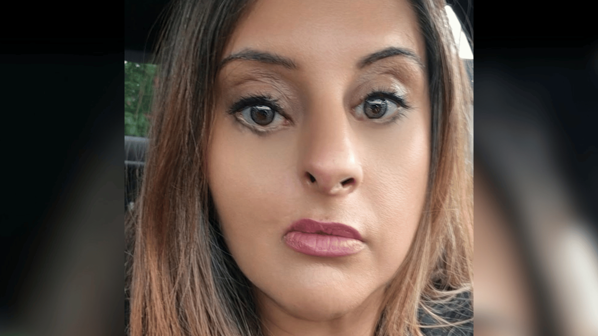 A selfie of Shabana sat in a car. She has a cleft lip and palate.